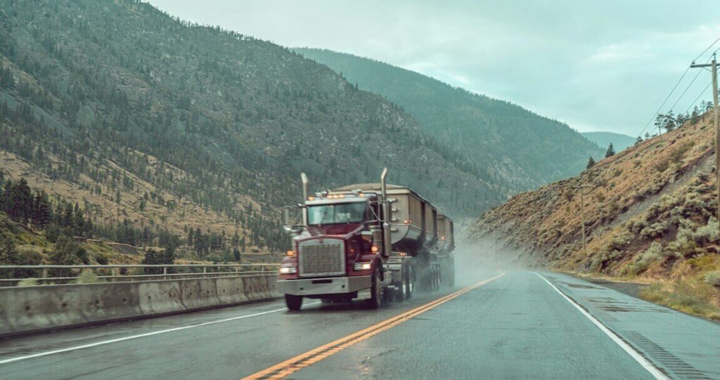 semi truck driving along a wet highway