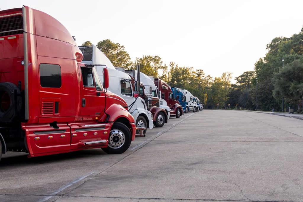 Row of semi trucks lined up at dusk in a truck stop parking area