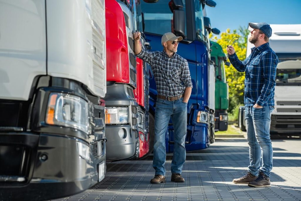 two drivers standing together at a truck parking lot